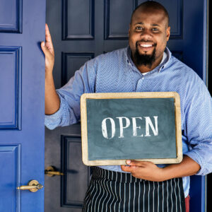 A business owner holds up an “Open” sign.