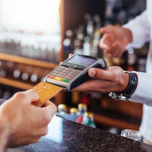 Person at a bar or restaurant paying for their tab using a credit card that’s processed by a POS system.